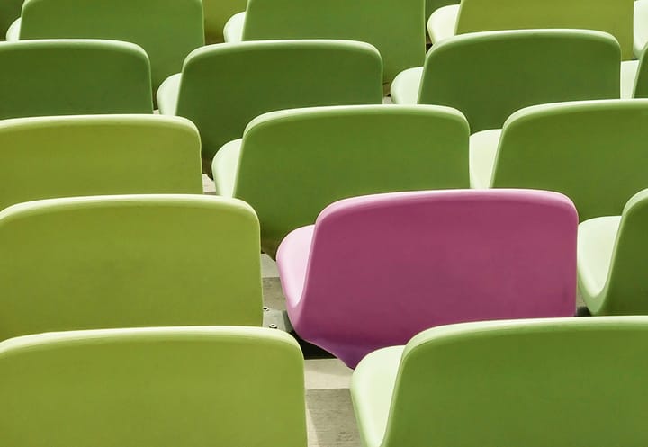 Rows of green seats with one pink seat standing out, symbolising selecting the best businesses.